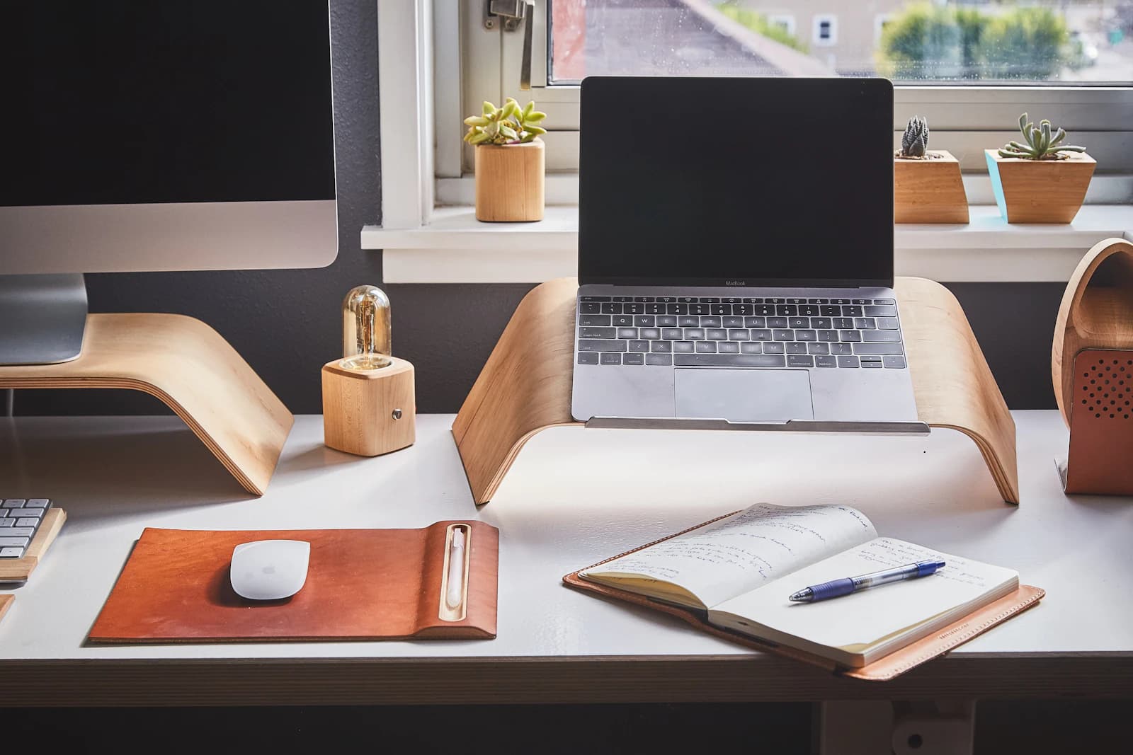 Workspace with a monitor, laptop, wooden accessories and plants